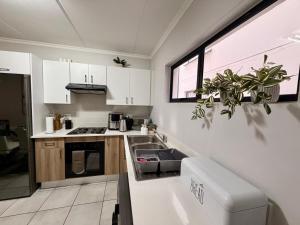 a kitchen with white cabinets and a sink and a window at Charming Oasis in the East in Boksburg