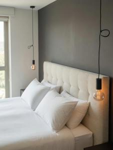 a bedroom with a white bed with two lights on it at BASIC MANSION plus with swimming pool & free parking in Šibenik +30 photos