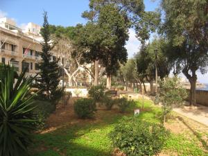a park with trees and bushes in front of a building at Valletta Gateway Maisonette in Valletta
