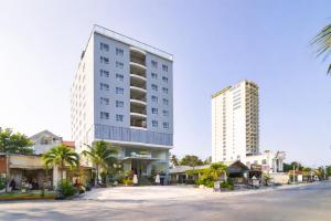 a tall white building next to a street with buildings at Palette Muine Boutique Hotel Near Mui Ne Beach in Mui Ne