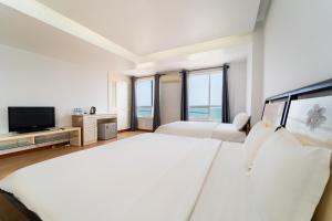 a white bedroom with two beds and a flat screen tv at Palette Muine Boutique Hotel Near Mui Ne Beach in Mui Ne +89 photos