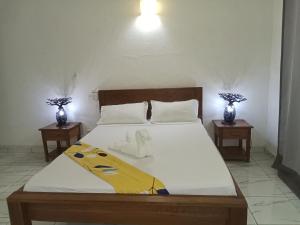 a bedroom with a bed with two tables and two vases at SummerDreams in Nosy Be
