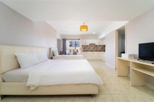 a bedroom with a white bed and a television at Palette Muine Boutique Hotel Near Mui Ne Beach in Mui Ne