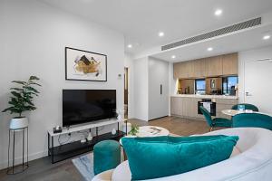 a living room with a white couch and a tv at Lumina Suites in Melbourne