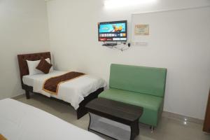 a room with a bed and a chair and a tv at Brindavana Stay in Bangalore +10 photos