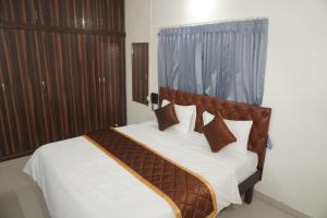 a bedroom with a bed with white sheets and brown pillows at Brindavana Stay in Bangalore