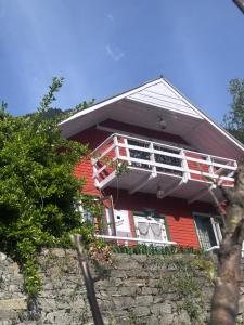 a red house with a balcony on top of a wall at Mistvale Cottage in Manāli