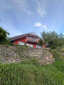 a red house on top of a stone wall at Mistvale Cottage in Manāli