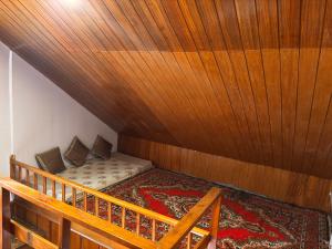 a bed in a room with a wooden ceiling at Mistvale Cottage in Manāli