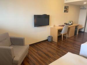 a living room with a couch and a desk and a television at Eastin Taipei Hotel in Taipei