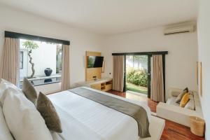 a bedroom with a white bed and a large window at The Seminyak Suites Private Villas in Seminyak