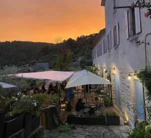 a patio with tables and umbrellas in front of a building at Gite de La Cueille - Chambre double in Ribes