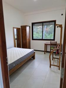 a bedroom with a bed and a desk and a window at OASIS Victoria Lounge! in Kandy