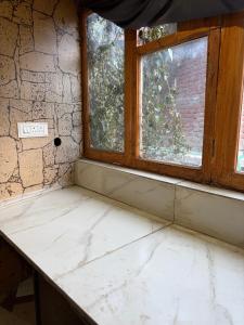 an empty room with two windows and a stone wall at Chilux Manali in Manāli