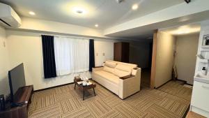 a living room with a couch and a table at Shinka Hotel Susukino in Sapporo
