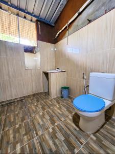 a bathroom with a toilet with a blue seat at Clay Hut by Ever Green Eco Resort in Wilpattu