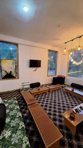 a living room with couches and tables and windows at Saathi Stay & Cafe in Vashisht