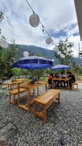 a group of picnic tables with blue umbrellas at Saathi Stay & Cafe in Vashisht