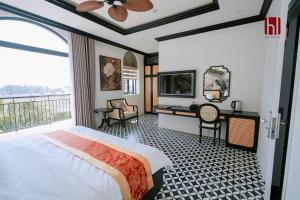 a bedroom with a bed and a desk and a balcony at HL Villa in Dong Hoi