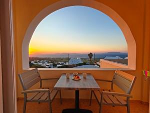 a table and chairs in a room with a window at Kiklamino Sunset Suites in Oia