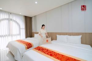 a woman standing between two beds in a hotel room at HL Villa in Dong Hoi