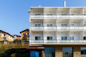 ein weißes Mehrfamilienhaus mit Balkon in der Unterkunft Petit Palace Tamarises in Getxo