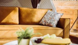 ein goldenes Sofa mit einem Kissen und einem Tisch in der Unterkunft Skyview Glamping Jacuzzi , Sauna in Ludwinów + 32 Fotos