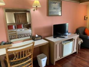 ein Wohnzimmer mit Fernseher und ein Schlafzimmer in der Unterkunft โรงแรมพิณ in Lampang
