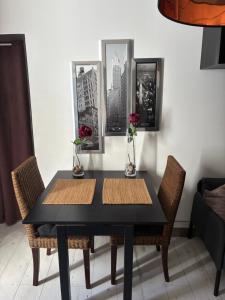 a black dining room table with chairs and pictures on the wall at Studio tout équipé, emplacement idéal in Saint-Raphaël