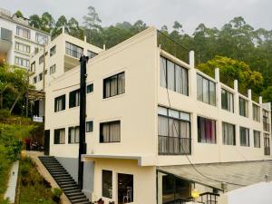 a large white building with windows and stairs at Veu Munnar Retreat - Valley View Rooms in Munnar