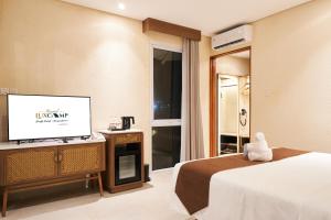 a hotel room with a bed and a flat screen tv at Grand Luxcamp Pangandaran by Horison in Pangandaran