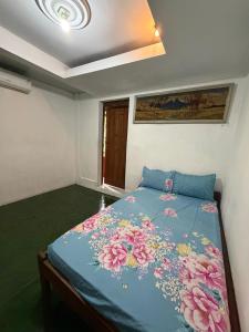 a bedroom with a blue bed with flowers on it at Rumah Ukhi Guest House in Yogyakarta