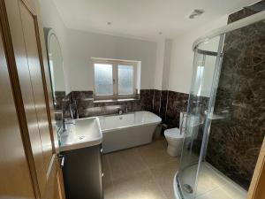 a bathroom with a tub and a sink and a shower at Stocks Lane Cottage in Welshampton +50 photos