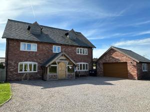 a large brick house with a garage at Stocks Lane Cottage in Welshampton
