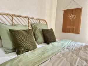a bed with green pillows on it in a room at Voilà Le Logat - Chambres & Gîtes in Sainte-Gemme