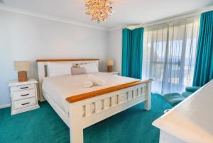 a white bedroom with a bed and a chandelier at West Beach House in Esperance