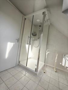 a shower with a glass door in a bathroom at chambres d hôtes Coco in Arnage