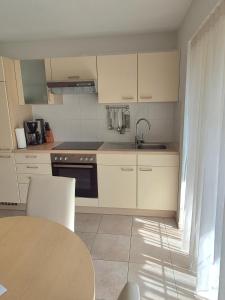 a kitchen with white cabinets and a sink and a table at Harlacher-Mühle in Stetten +14 photos