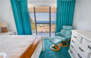 a bedroom with a bed and a chair and a window at West Beach House in Esperance