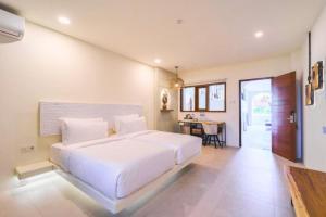 a bedroom with a large white bed and a table at Dwayne 1 BR Standard Room in Kuta Lombok