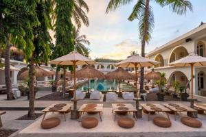 a resort with tables and umbrellas and a pool at Dwayne 1 BR Standard Room in Kuta Lombok