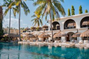 a resort with palm trees and a swimming pool at Dwayne 1 BR Standard Room in Kuta Lombok