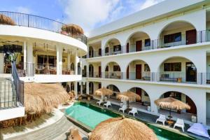 a resort with a swimming pool and straw umbrellas at Dwayne 1 BR Standard Room in Kuta Lombok +21 photos