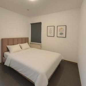 a white bed in a room with two pictures on the wall at Midi station in Brussels
