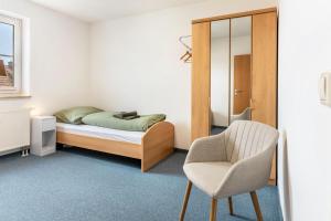 a bedroom with a bed and a chair at Komfortable 3-Zimmer-Fewo in Sonneberg