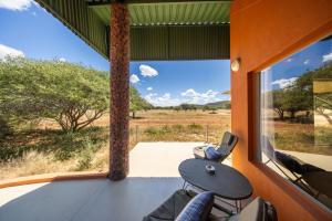 a room with a view of the savannah from a window at Okonjima Plains Camp in Otjiwarongo
