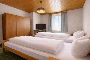 a hotel room with two beds and a television at Golf Hotel Des Alpes in Samedan