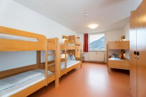 a room with three bunk beds and a window at Jugendherberge Bad Urach in Bad Urach