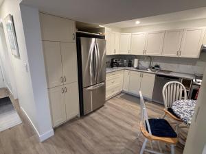 a kitchen with white cabinets and a stainless steel refrigerator at Private Guest Suite In Colwood in Colwood
