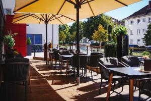 ein Restaurant mit Tischen, Stühlen und Sonnenschirmen in der Unterkunft Hotel Global Inn in Wolfsburg